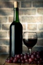 Wine bottle and glass on a wooden table with bricks wall background with grape Royalty Free Stock Photo