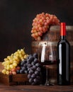 Wine bottle, grapes, glass of red wine and old barrel