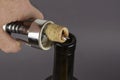 Wine bottle, hand with a corkscrew and a broken cork on a gray b Royalty Free Stock Photo