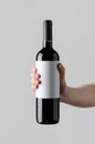 Wine Bottle Mock-Up. Blank Label - Male hands holding a wine bottle on a gray background Royalty Free Stock Photo