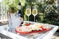 Wine bottle mockup with blank stickers. Ice cooler, two glasses of champagne and plate of delicious dessert on glass table Royalty Free Stock Photo