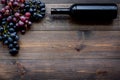 Wine bottle near bunches of red and black grapes on dark wooden background top view copyspace Royalty Free Stock Photo