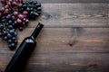 Wine bottle near bunches of red and black grapes on dark wooden background top view copyspace Royalty Free Stock Photo