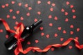 Wine bottle with a red satin ribbon bow. Valentine`s Day. On a concrete background with paper hearts Royalty Free Stock Photo