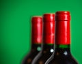 Wine bottle series of three red bottles with green background copy space