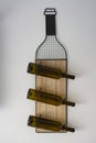 A wine bottle stand with three bottles hangs on a wall. Royalty Free Stock Photo