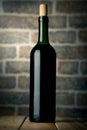 Wine bottle on a wooden table with bricks wall background Royalty Free Stock Photo