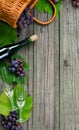 Wine bottles with grapes, basket, two wineglasses on rustic wood. Vertical wine making Royalty Free Stock Photo