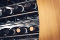 Red wine bottles laid horizontally in a wine rack with wood and metal bars