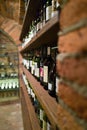 Wine cellar with various bottles on wooden and brick stone shelves