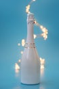 Wine champagne bottle with defocused lights on blue background. Birthday and New Year holidays celebration concept. Front view. Royalty Free Stock Photo