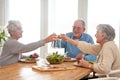 Wine, cheers and senior friends at brunch in home with smile, celebration and bonding in retirement. Food, drinks and Royalty Free Stock Photo