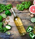 Wine concept. Bottle and glass of young white bio wine with green grapes, grapefruit and other fruit on an old wooden table