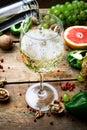 Wine concept. Glass of young white bio wine with green grapes, grapefruit and other fruit on an old wooden table