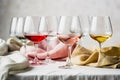Different kind of wine in glasses on table with textile tablecloths on neutral grey background