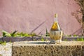 Wine flask covered with straw resting on a tufa stone block against a a wall - image with copy space Royalty Free Stock Photo