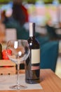 Wine glass and bottle of red wine on a wooden table over blurred background. Restaurant service, eating out concept Royalty Free Stock Photo