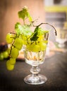 Wine glass with a bright grapes on a branch and leaves on a dark wooden background close up Royalty Free Stock Photo