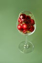 Wine glass filled with red christmas balls on green background Royalty Free Stock Photo