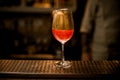 Wine glass with fizzy drink decorated with gold stands on bar counter