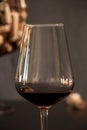 Wine glass in the foreground with corks from the background bottles in dark tones Royalty Free Stock Photo