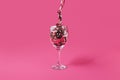 Wine glass with a glossy ribbon on pastel pink background. Aesthetic celebration concept.