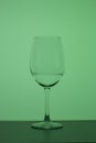 Wine glass on a long stem. A little drink is poured into it. In back green