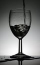 Wine glass with a pouring water standing on a black table Royalty Free Stock Photo