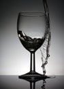 Wine glass with a pouring water standing on a black table Royalty Free Stock Photo