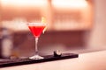 A wine glass with a red drink and a slice of lemon stands on the bar countertop.