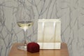 Wine glass and red jewerly box on wooden table over grunge wall. Holiday background.