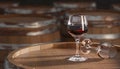 Wine glass of red wine on old wooden barrel at winery. Wine glasses and barrels. Traditional winemaking and wine tasting. 3d Royalty Free Stock Photo