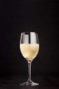 Wine glass with white wine on elegant dark black wooden background, copy space, vertical. Royalty Free Stock Photo