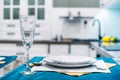 Wine glass and white plates on a blue tablecloth. Table setting for one person at home. Foreground Royalty Free Stock Photo