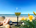 Beach scene Wine glass and women hat on wooden bench on beach blue sky white sand yellow flowers  green sea water summer holiday Royalty Free Stock Photo