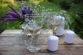 Wine glasses decorated with flowers, bouquet of lavender, veronica flowers in vase, candles on a wooden table in the summer garden Royalty Free Stock Photo