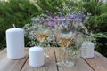 Wine glasses decorated with flowers, bouquet of lavender, veronica flowers in vase, candles on a wooden table in the summer garden Royalty Free Stock Photo