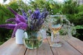 Wine glasses decorated with flowers, bouquet of lavender, veronica flowers in vase, candles on a wooden table in the summer garden Royalty Free Stock Photo