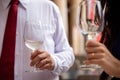 Wine glasses held in hand by a man and a woman, both wearing a wedding ring on their ring finger