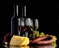 Wine, grapes, cheese and sausage on black background