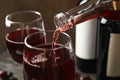 Wine is poured from bottle in glass on wooden table, close up Royalty Free Stock Photo