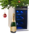 Wine refrigerator and bottle of champagne under Christmas tree. Royalty Free Stock Photo