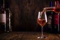 Wine tasting. Rose wine pouring into glass on wooden background with selection of red, white and rose wines in bottles Royalty Free Stock Photo