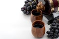 Wine tasting and winemaking tradition concept with grapes and wooden cups filled with aged red wine from an wood barrel or keg Royalty Free Stock Photo