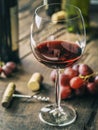 Wine testing. Wine glass, grapes and bottle opener on old wooden table Royalty Free Stock Photo