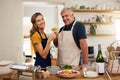 Wine, toast and senior couple in a kitchen for cooking, bonding and celebrating their relationship in their home. Happy Royalty Free Stock Photo
