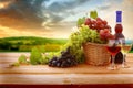 Wine and vineyard in sunset.Colorful grapes in basket. Barrel, red and white wine bottle and glass on wooden table Royalty Free Stock Photo