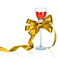 Wine in wineglass and golden satin gift bow, on white Royalty Free Stock Photo