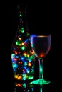 A wineglass and a bottle of lighted garland