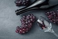 Wineglass, bottle and ripe grapes on black stone background.